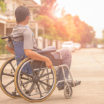 henkilö pyörätuolissa, leveällä, avoimella ja tasaisella tiellä